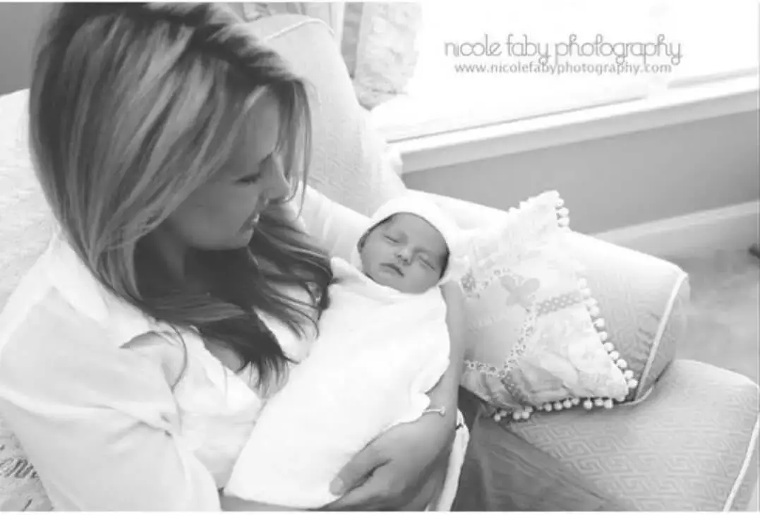 Mother holding newborn baby wrapped in blanket, showcasing love, bonding, and family moments at home.