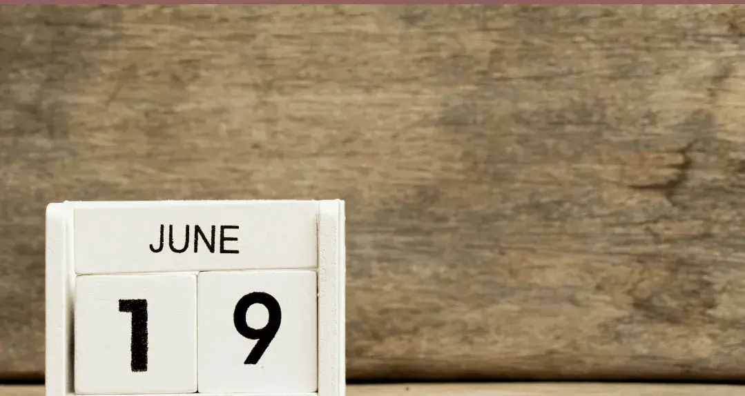 A wooden block calendar displays the date "June 19" against a rustic wooden background.