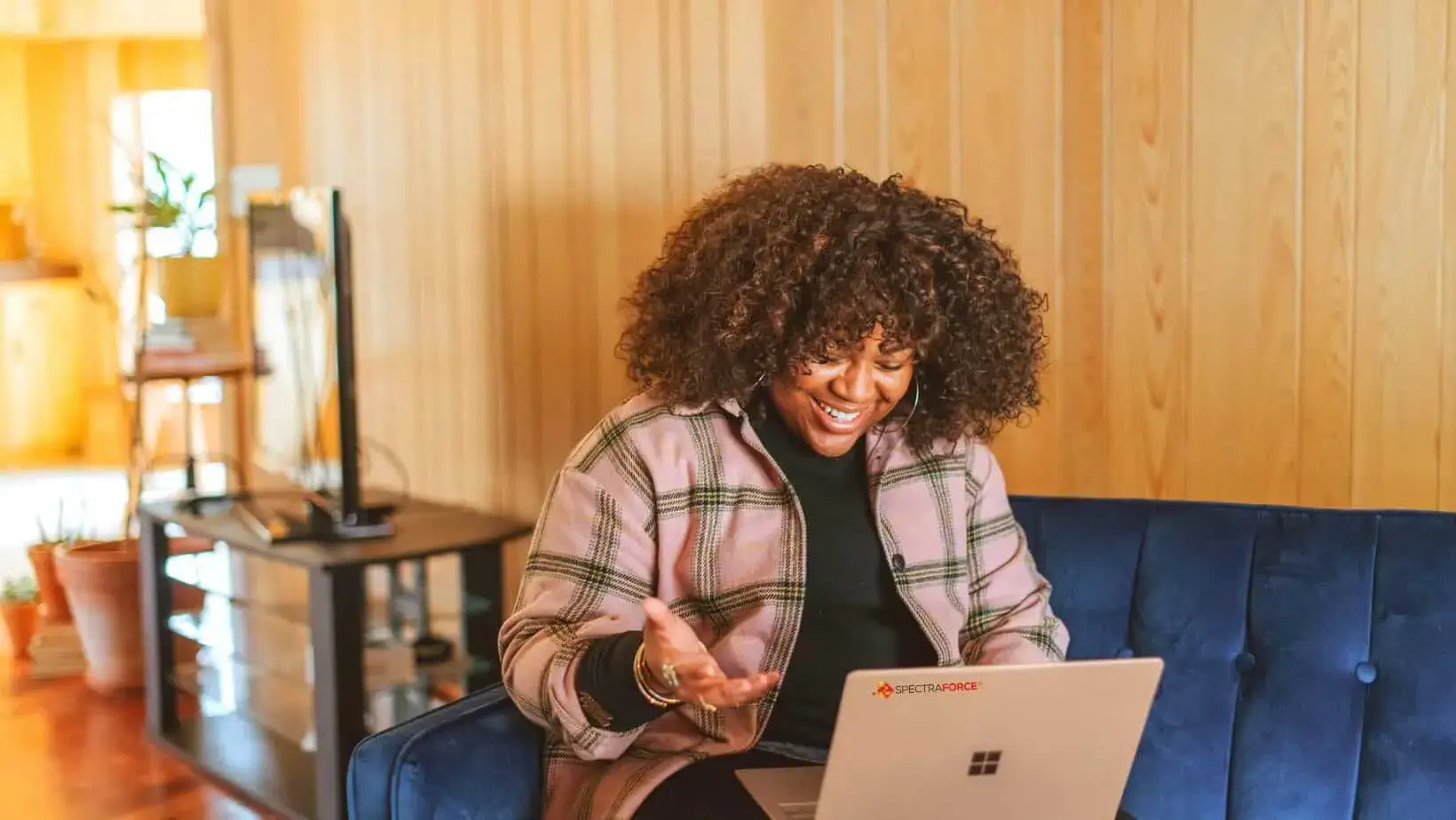 Cheerful woman smiling during a video call while working remotely on a laptop