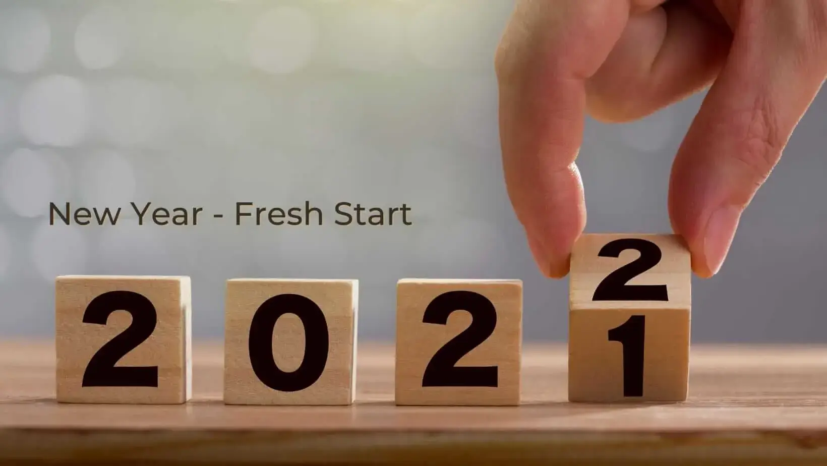 Hand flipping wooden block from 1 to 2, showing the year 2022.