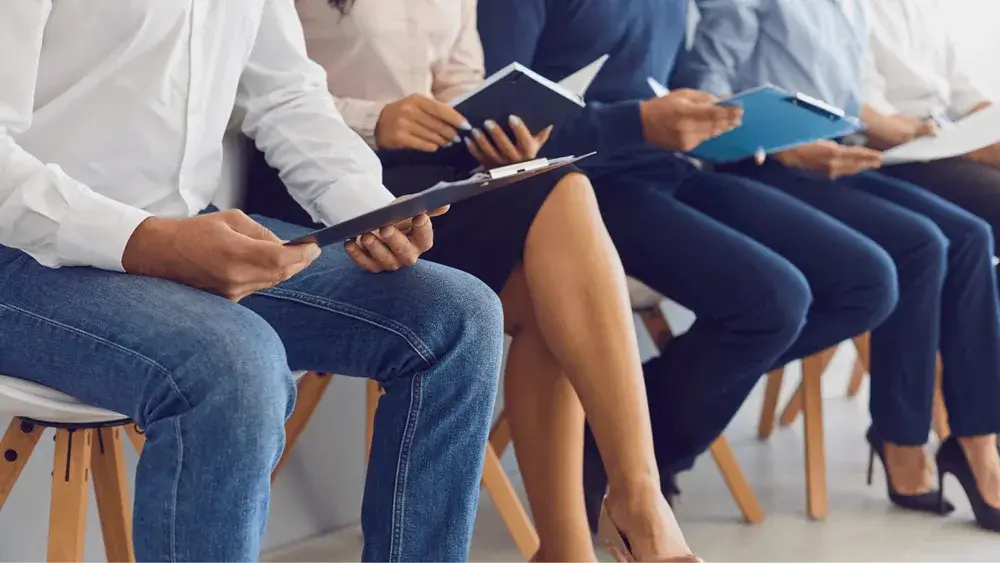 Several interviewees seated with CVs in hand, waiting for their turn in a job interview.