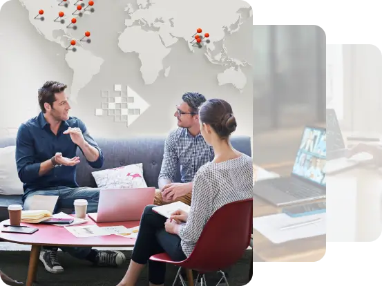 A group of three people engaged in a discussion around a coffee table with laptops, papers, and a world map in the background, symbolizing teamwork, collaboration, and global perspective.