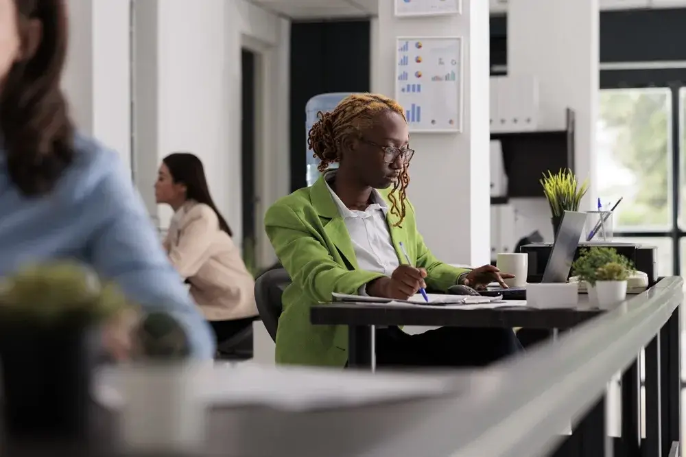 Employee working on a laptop with a financial report on screen, reflecting a business analysis context.
