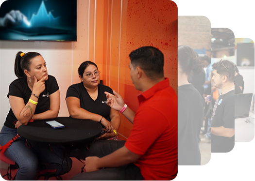 Three individuals engage in a conversation around a black table, with a colorful background and a screen displaying abstract graphics.