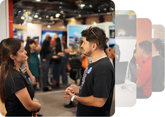 Two individuals engage in conversation at a vibrant event, with a bustling crowd and colorful displays in the background.