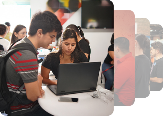 A group of people engaged in discussion around a laptop at a bright, modern workspace filled with casual attire.