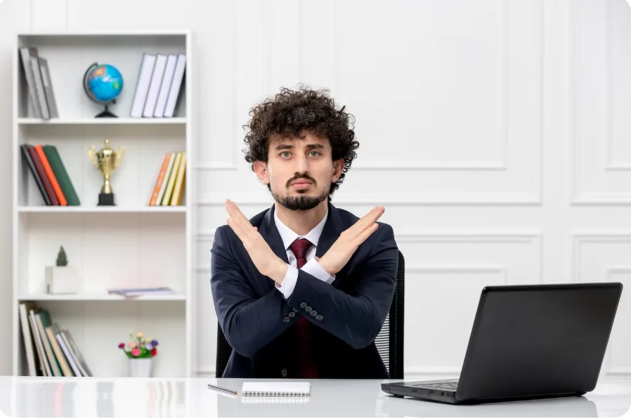January hiring freeze concept: Man in corporate attire indicating a “no”