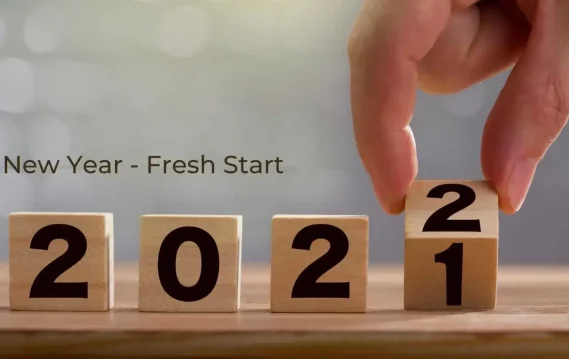 Hand flipping wooden block from 1 to 2, showing the year 2022.
