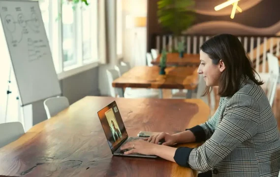 Woman attending a video call on a laptop in a stylish, well-lit workspace.