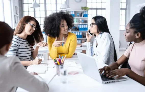 Blog-Banner 5 women discussing and taking notes sitting on a table