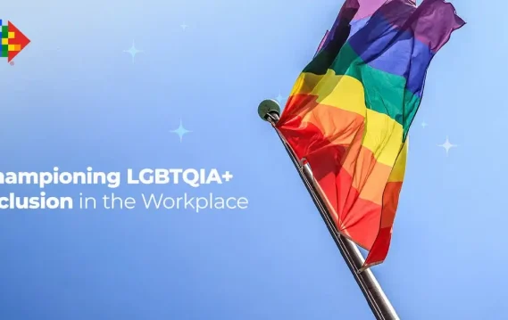 Championing-Inclusion-in-the-Workplace Rainbow pride flag waving under blue sky, promoting LGBTQIA+ inclusion and diversity in the workplace.