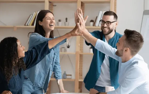 Diverse team celebrating success with high-fives, promoting inclusive workplace culture and employee collaboration.