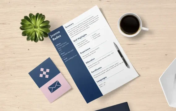 Flat lay of a resume on desk with coffee, plant, business card, pen, and office supplies