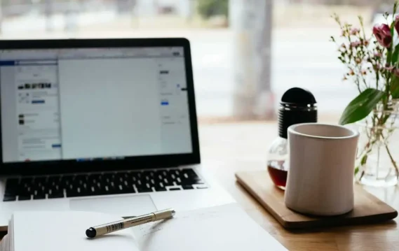 Workspace with laptop, coffee, and flowers, representing productivity, remote work, and digital lifestyle.