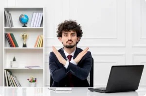 January hiring freeze concept: Man in corporate attire indicating a “no”