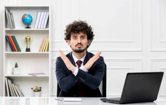 January hiring freeze concept: Man in corporate attire indicating a “no”