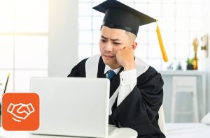 Skill-based hiring concept: Frustrated man in graduation cap looking into his laptop