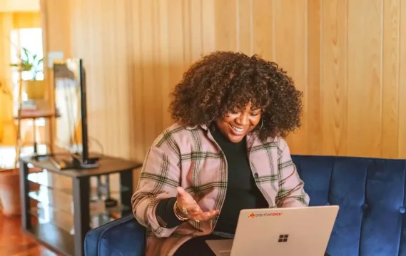 Cheerful woman smiling during a video call while working remotely on a laptop