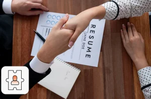 Staff augmentation concept: Two people seated across the table, shaking hands over a resume placed on the table