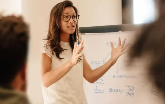 Women explaining the characteristics of a great leader with a whiteboard.