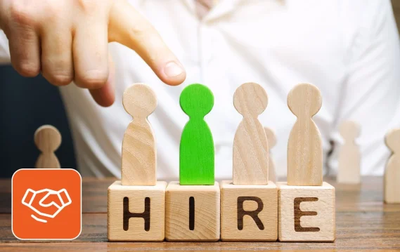 Person selecting from wooden pegs spelling hire indicating staffing services
