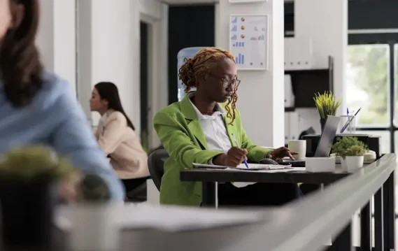 Employee working on a laptop with a financial report on screen, reflecting a business analysis context.
