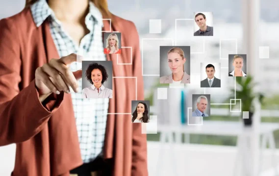 innovative-staffing-solutions A woman in business attire interacts with a digital interface displaying a network of diverse professional headshots, representing a virtual staffing or recruitment solution.